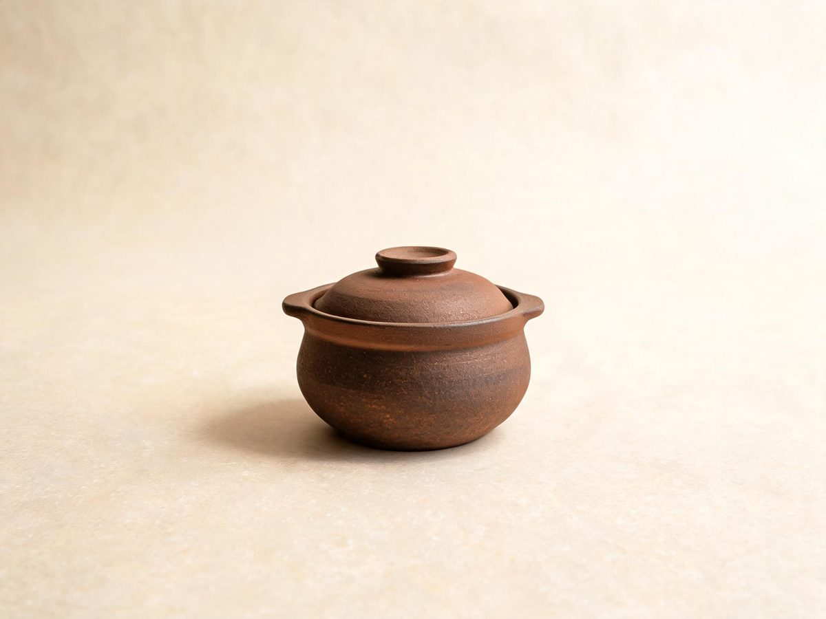 Concept visual: a traditional Korean ttukbaegi stone pot with its lid on a warm studio backdrop
